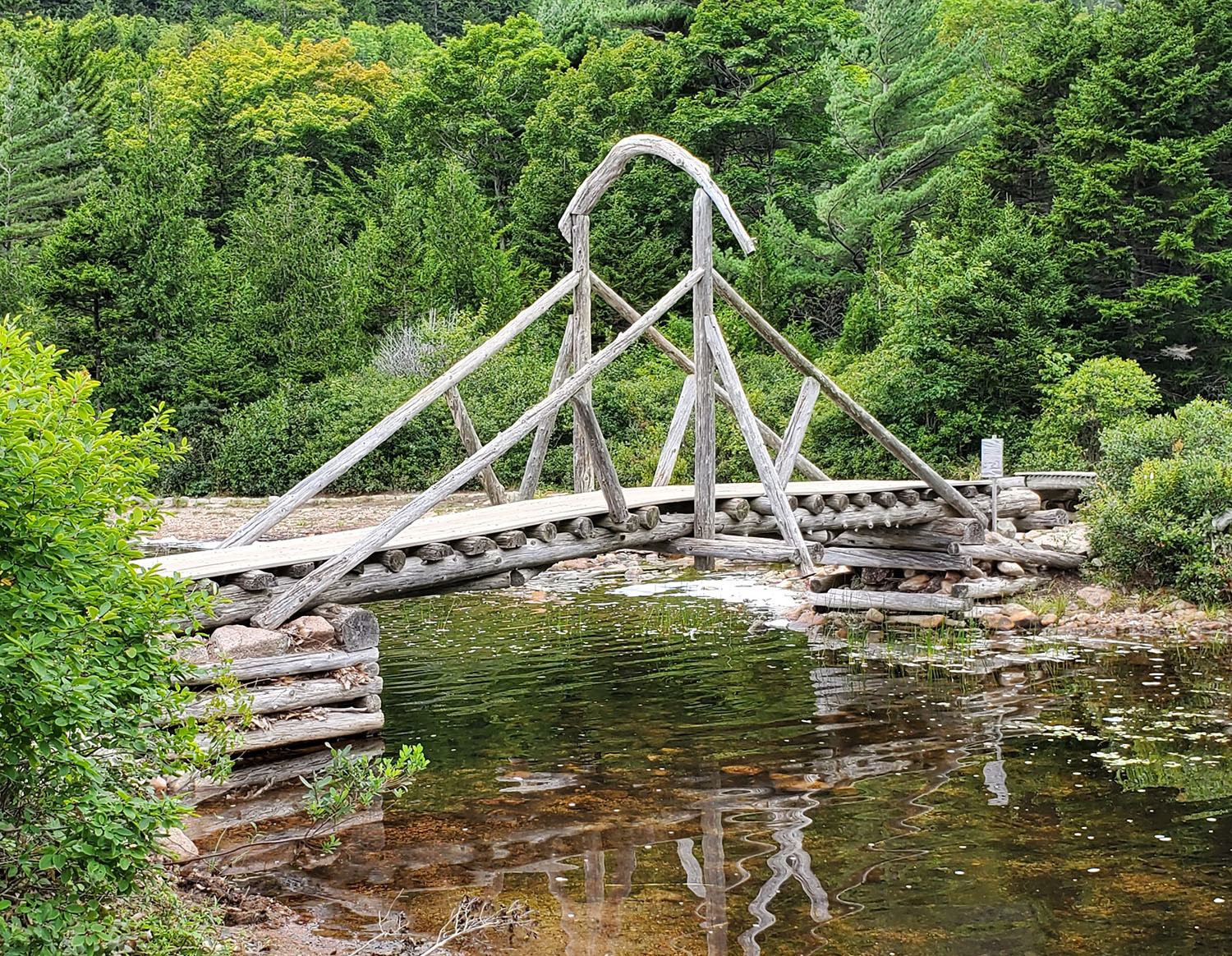 rustic wooden bridge over a stream in the woods