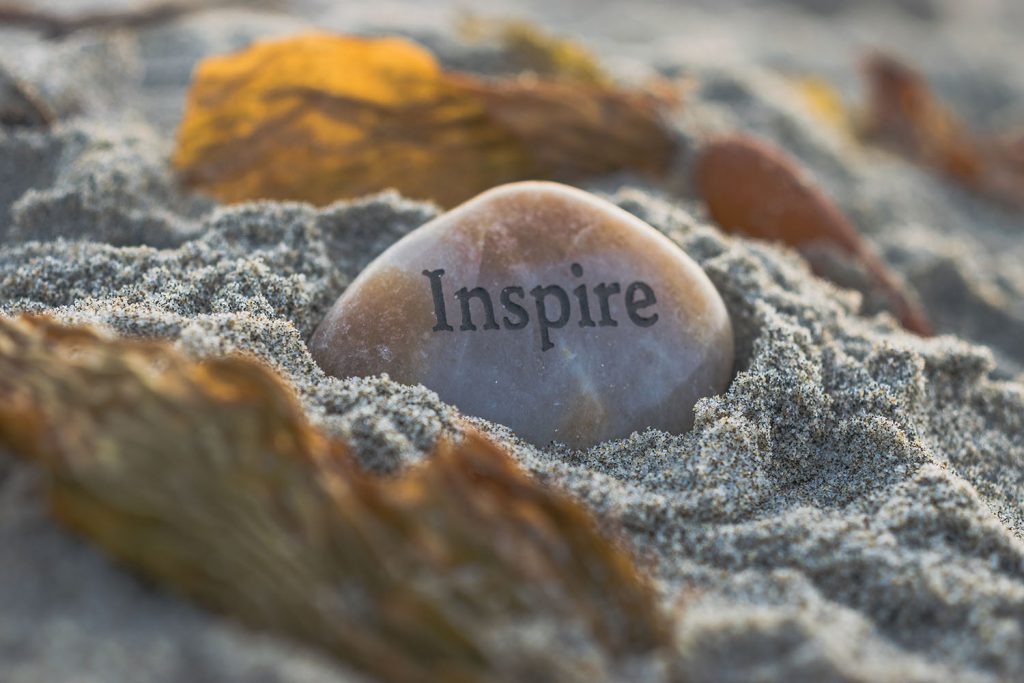 a rock on the beach with the word inspire etched on it